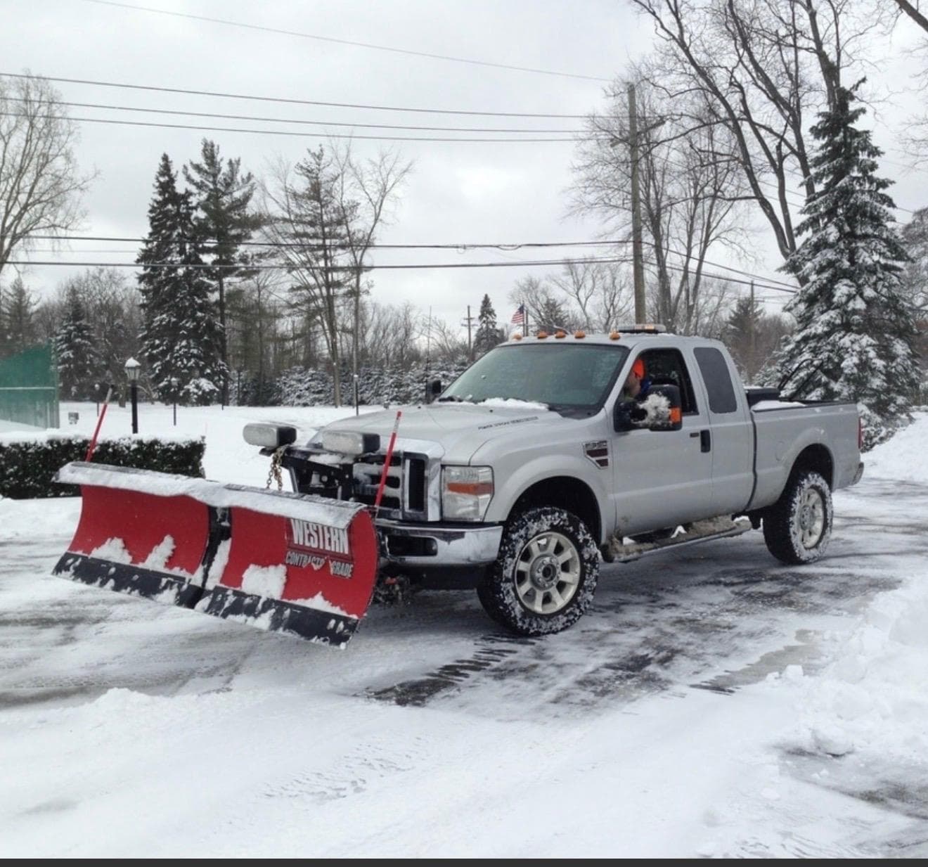 A pickup truck with a Western snow plow clearing a snow-covered lot